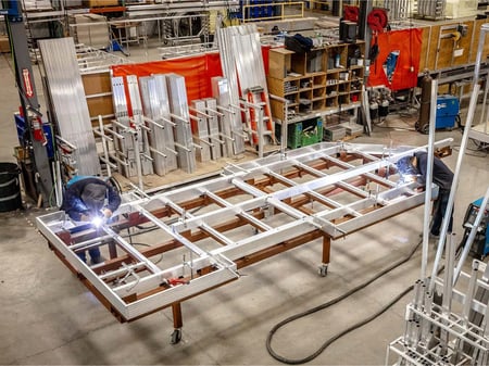 Two workers are welding the frame of a custom Yetti Fish House