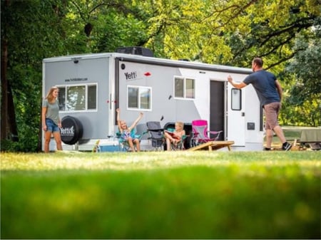 Family is enjoying a summer day outside a gray colored Yetti Fish House Grand Escape.
